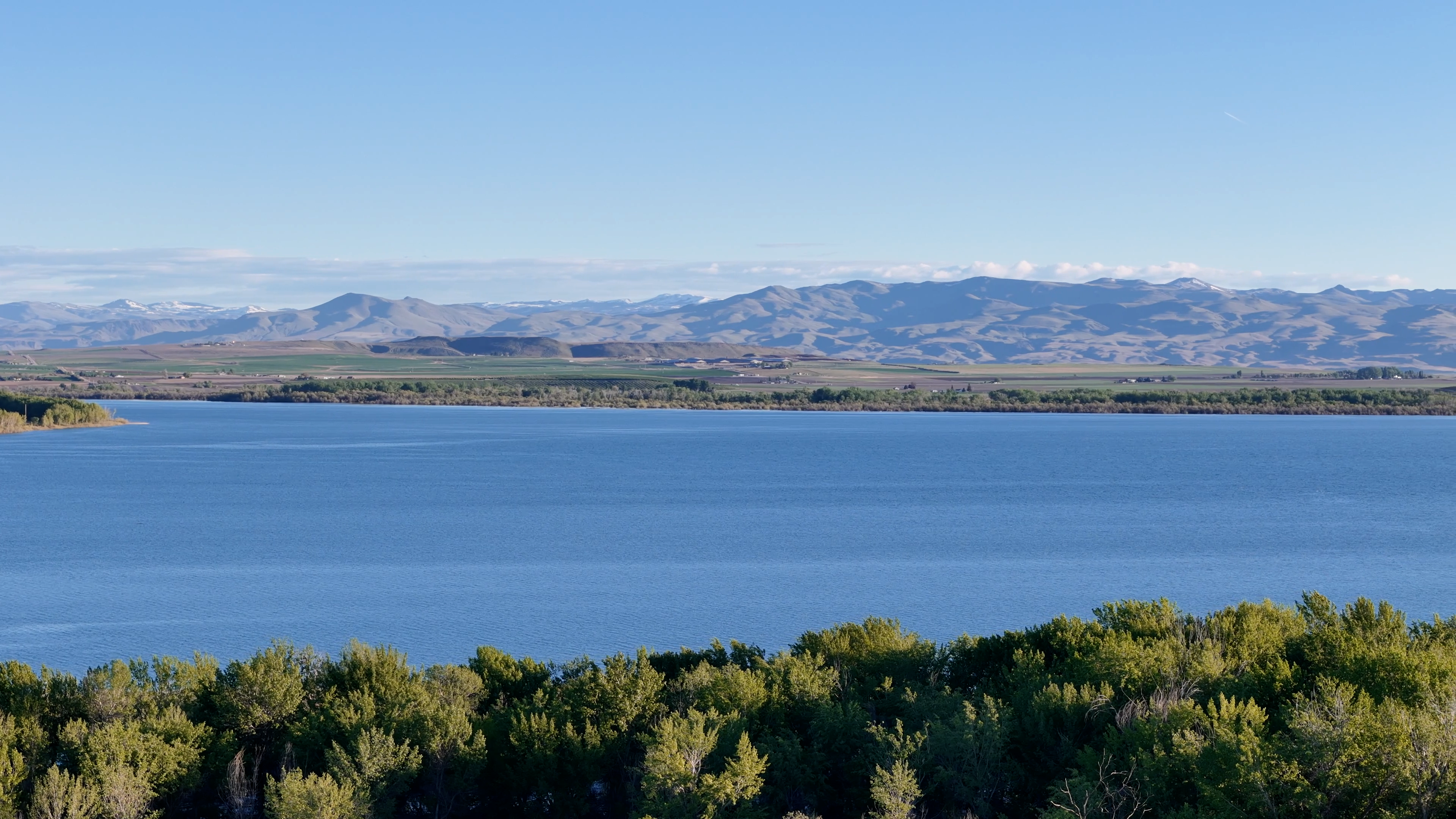 Scenic view of Lake Lowell with calm water, surrounding trees, and distant hills under a clear blue sky.