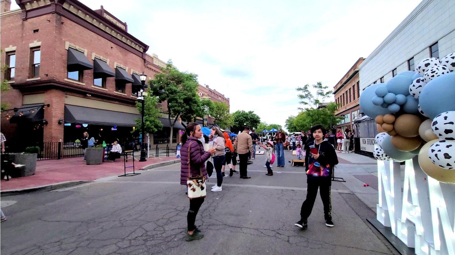 People enjoying Downtown Nampa’s Third Thursday event with food, games, and local businesses on a closed street lined with historic buildings.